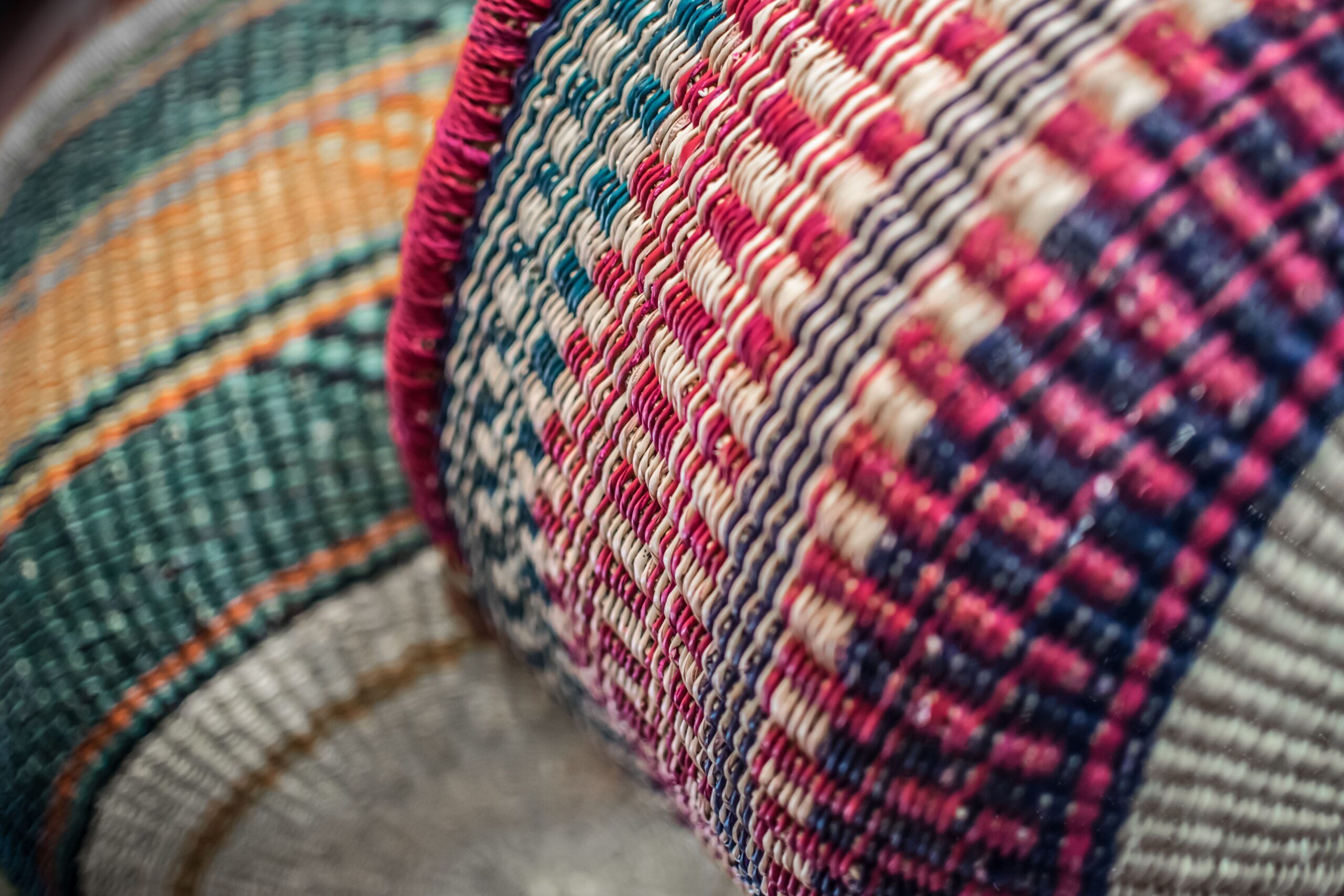 Close-up of a colorful woven basket, featuring intricate red, blue, and natural fibers in a zigzag pattern, conveying a sense of craftsmanship and tradition.
