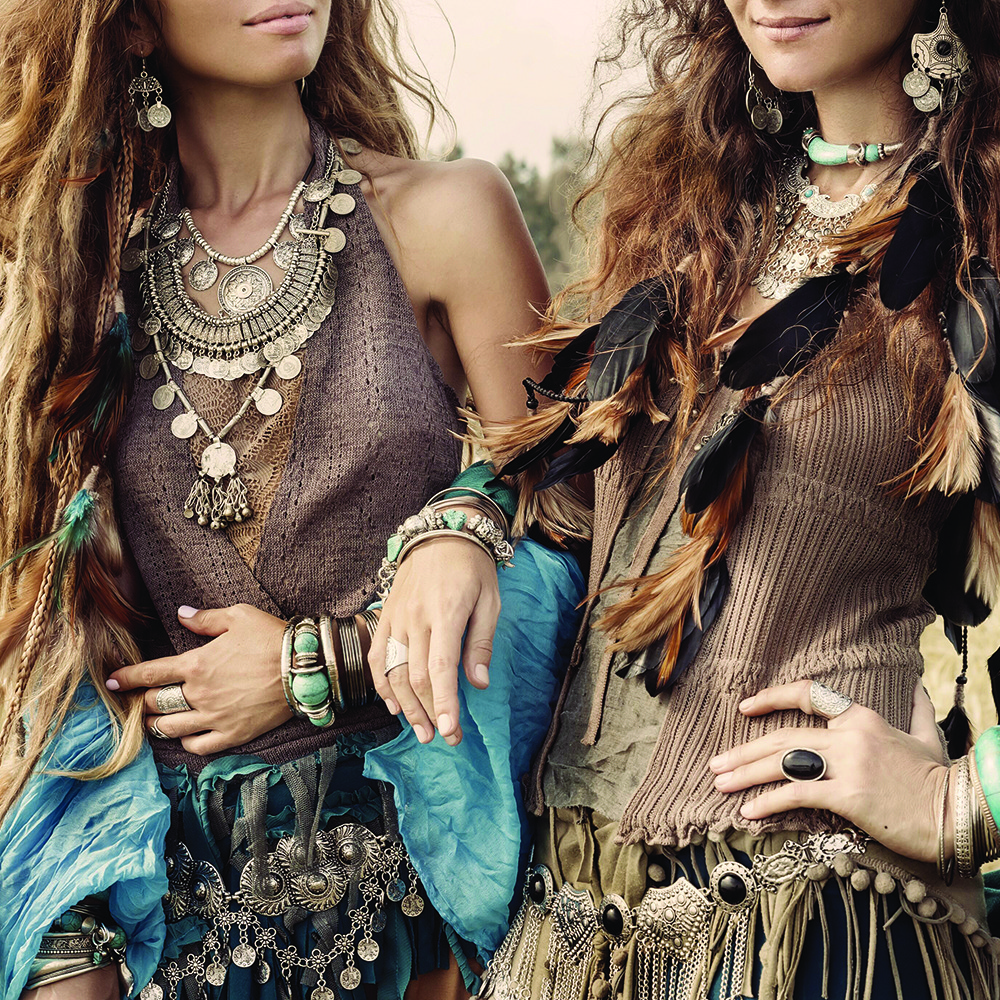 Two women in bohemian attire stand in a natural setting.